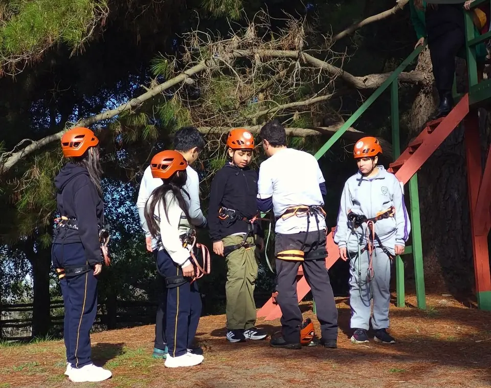 Participantes con arnés y casco preparados para arborismo